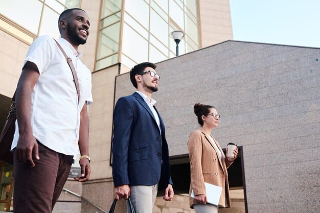 A diverse group of people, including real estate agents and potential buyers, gathered in a modern office space, all wearing VR headsets and immersed in virtual property tours, with digital displays showing the properties being viewed.